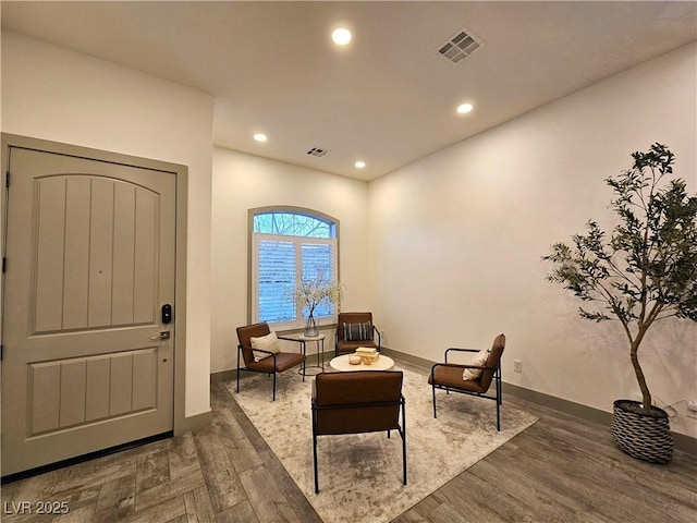 living area with recessed lighting, visible vents, baseboards, and wood finished floors