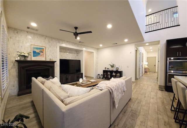 living area featuring light wood-style floors, recessed lighting, a fireplace, and visible vents