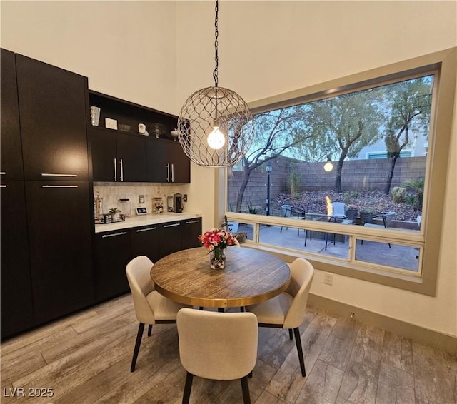 dining area with light wood-style flooring and a towering ceiling