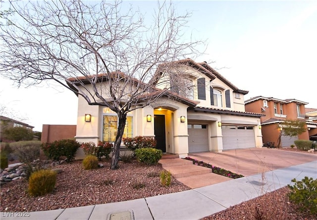 mediterranean / spanish home with a tiled roof, stucco siding, an attached garage, and concrete driveway