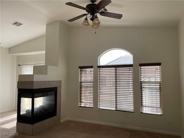 unfurnished living room featuring a ceiling fan, visible vents, carpet floors, vaulted ceiling, and a tiled fireplace