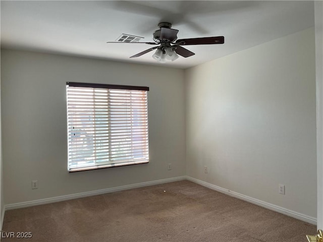 carpeted spare room featuring baseboards and ceiling fan