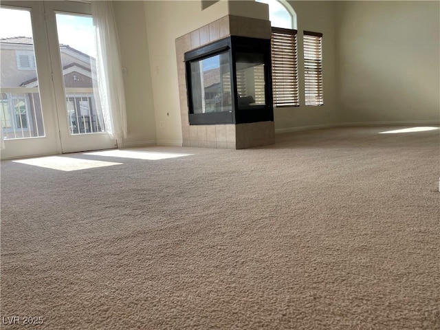 spare room featuring baseboards, carpet, a high ceiling, and a fireplace