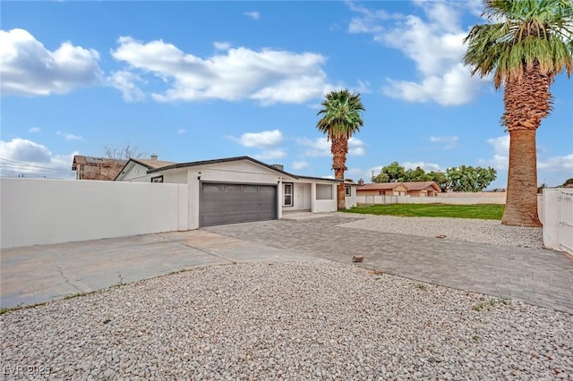 view of front of house featuring an attached garage, decorative driveway, and fence