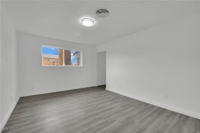 unfurnished room with visible vents, baseboards, and wood finished floors