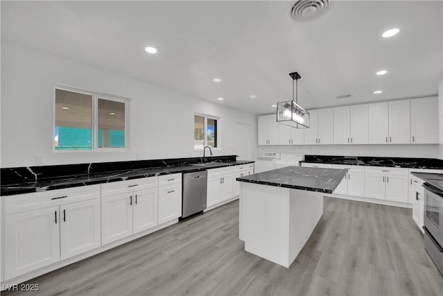 kitchen featuring visible vents, washer / clothes dryer, appliances with stainless steel finishes, white cabinets, and light wood finished floors