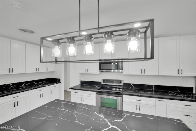 kitchen featuring white cabinetry, dark stone counters, and stainless steel appliances