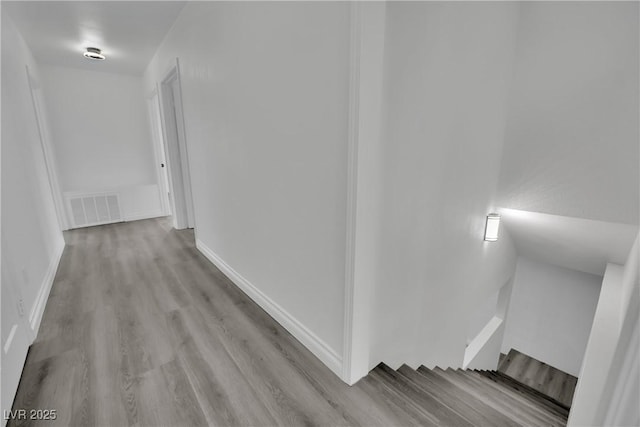 hallway featuring visible vents, baseboards, and wood finished floors