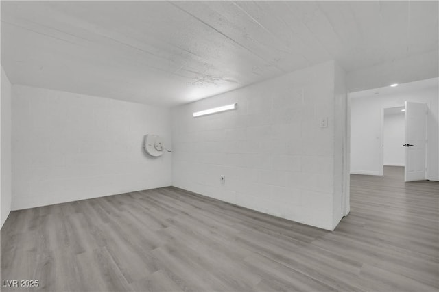 spare room with concrete block wall and wood finished floors