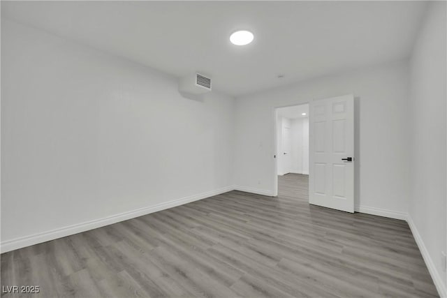 empty room featuring visible vents, baseboards, and wood finished floors