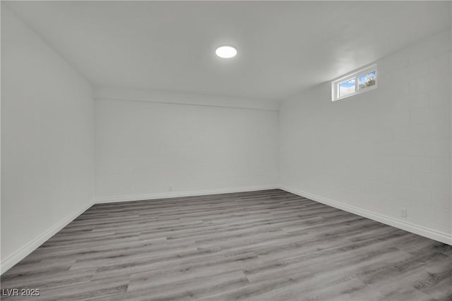 interior space featuring concrete block wall, baseboards, and wood finished floors