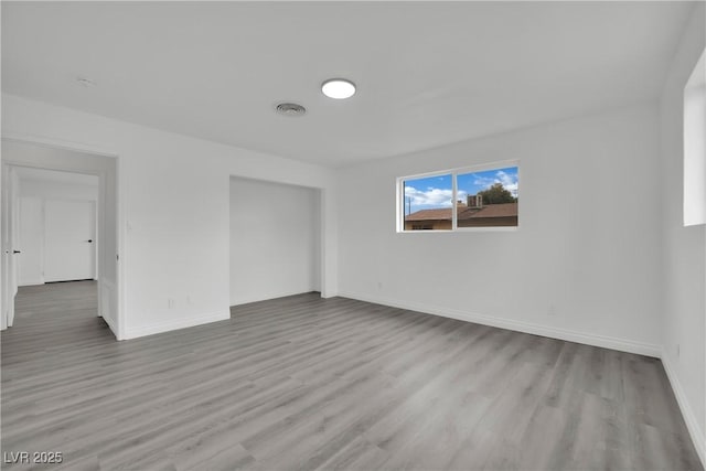 empty room featuring visible vents, baseboards, and wood finished floors