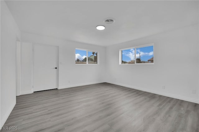 unfurnished room with visible vents, baseboards, and wood finished floors