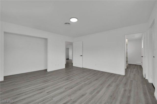 empty room featuring visible vents, baseboards, and wood finished floors