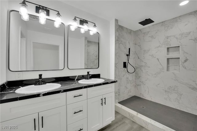 bathroom featuring a sink, a marble finish shower, marble finish floor, and double vanity