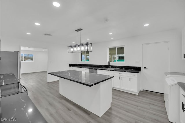 kitchen with stainless steel appliances, plenty of natural light, white cabinets, and light wood-style flooring