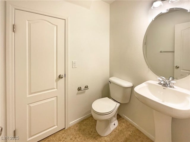 bathroom with toilet, baseboards, and a sink