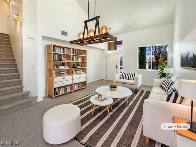 living area with visible vents, carpet, stairway, a high ceiling, and a notable chandelier