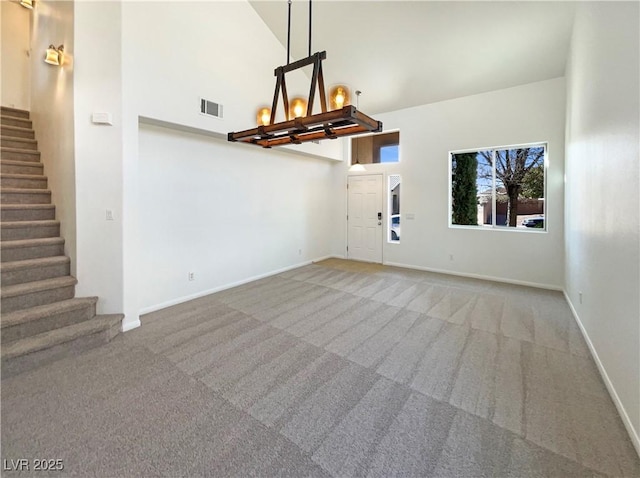 interior space featuring stairway, a high ceiling, visible vents, and carpet floors