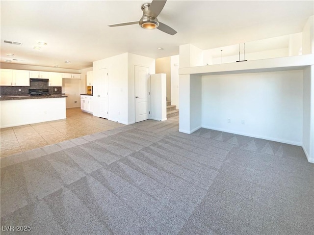 unfurnished living room with visible vents, light carpet, a ceiling fan, baseboards, and stairs