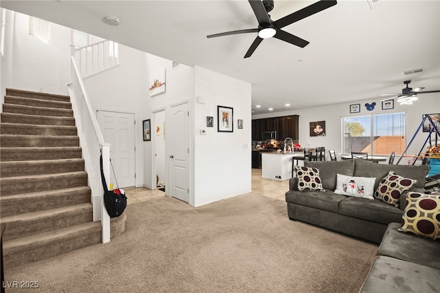 living room featuring light tile patterned floors, visible vents, light colored carpet, and stairway