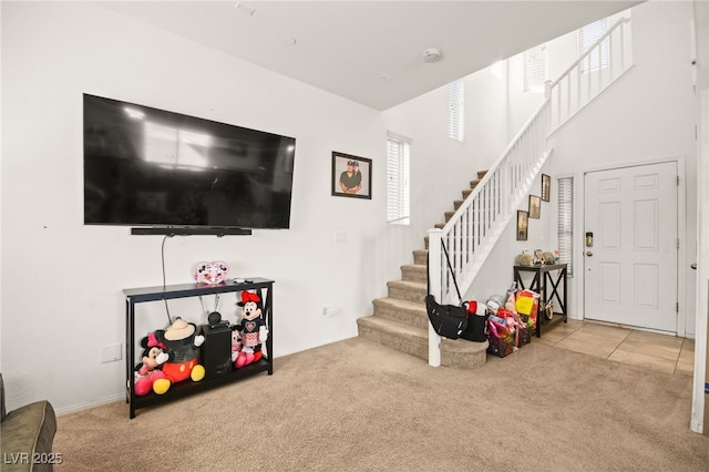 carpeted living area featuring stairway and a high ceiling