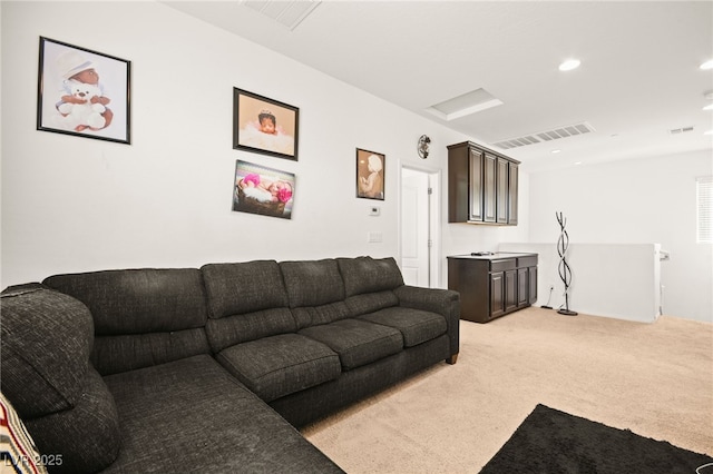 living area featuring visible vents, light colored carpet, and attic access