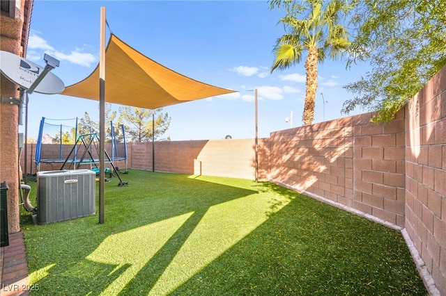 view of yard with central air condition unit, a trampoline, and a fenced backyard