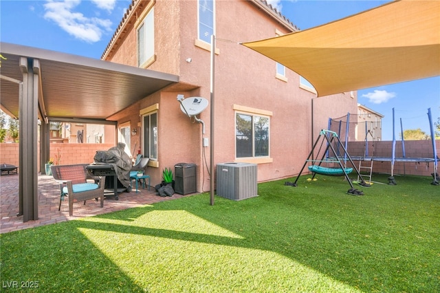 rear view of property with stucco siding, central air condition unit, a trampoline, and a patio area