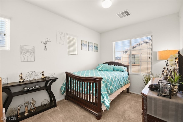 carpeted bedroom with visible vents, multiple windows, and baseboards