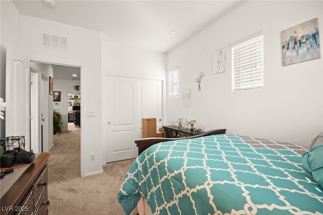 bedroom with a closet, visible vents, and light colored carpet