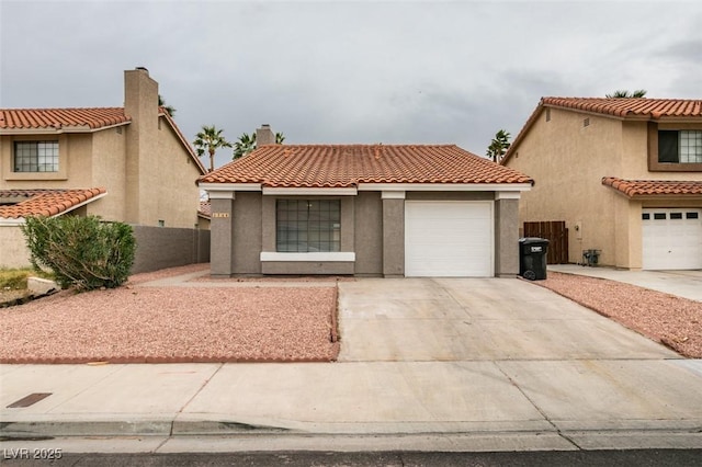 mediterranean / spanish-style home featuring fence, a tile roof, concrete driveway, stucco siding, and a garage