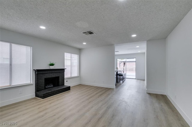 unfurnished living room featuring wood finished floors, a fireplace, visible vents, and baseboards