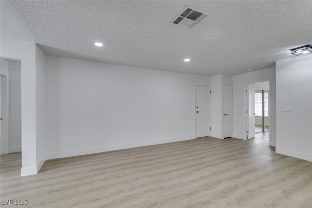 spare room with visible vents, a textured ceiling, recessed lighting, light wood finished floors, and baseboards