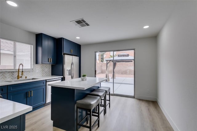 kitchen featuring tasteful backsplash, visible vents, a kitchen breakfast bar, stainless steel appliances, and a sink