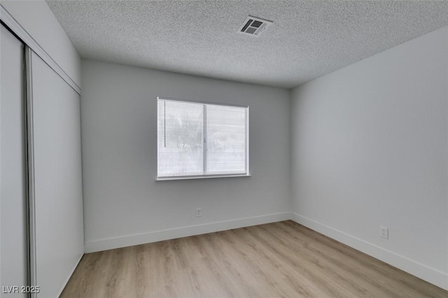 unfurnished bedroom featuring a closet, visible vents, light wood finished floors, and baseboards