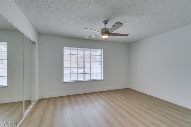 unfurnished bedroom with a ceiling fan, baseboards, light wood-style floors, a closet, and a textured ceiling