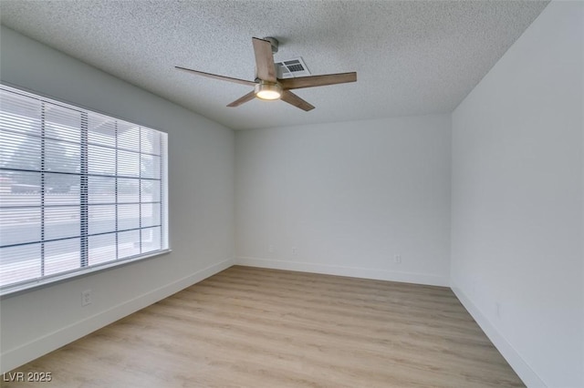 spare room featuring baseboards, a textured ceiling, a ceiling fan, and light wood-style floors