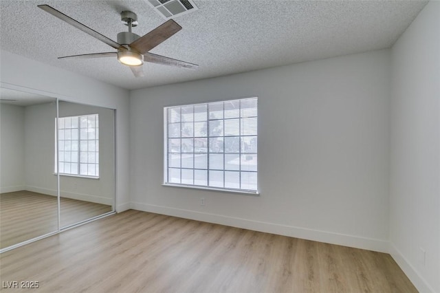 unfurnished bedroom with visible vents, baseboards, a closet, and light wood-style flooring