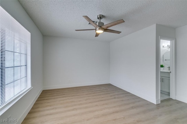 empty room featuring baseboards, a textured ceiling, a ceiling fan, and light wood-style floors