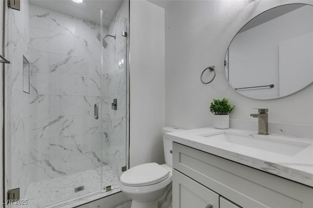 bathroom featuring a marble finish shower, toilet, and vanity