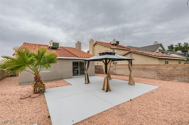 rear view of property with central AC unit, fence, stucco siding, a gazebo, and a tiled roof