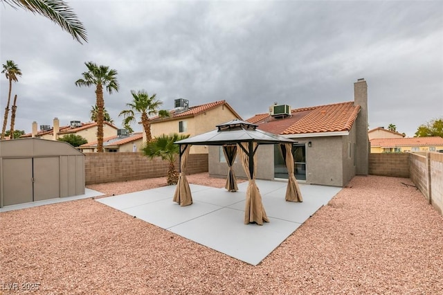 rear view of property featuring a tile roof, a gazebo, a storage shed, an outdoor structure, and a patio area