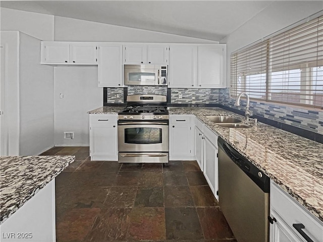 kitchen with a sink, dark stone countertops, tasteful backsplash, stainless steel appliances, and vaulted ceiling