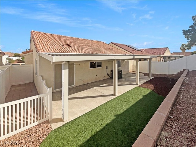 rear view of house with stucco siding, a patio, a fenced backyard, central AC unit, and a tiled roof