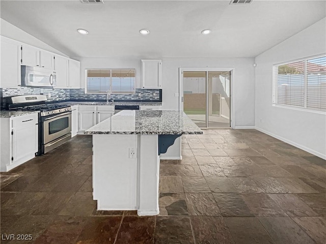 kitchen featuring lofted ceiling, light stone counters, decorative backsplash, white cabinets, and gas stove