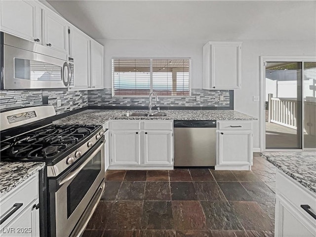 kitchen with tasteful backsplash, light stone countertops, appliances with stainless steel finishes, white cabinetry, and a sink