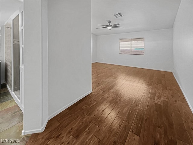 spare room featuring visible vents, baseboards, a ceiling fan, and wood-type flooring