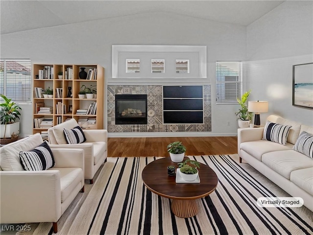 living area featuring a tile fireplace, lofted ceiling, and wood finished floors