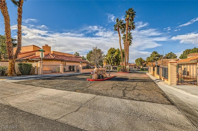 view of road featuring a gated entry, curbs, traffic signs, and a gate